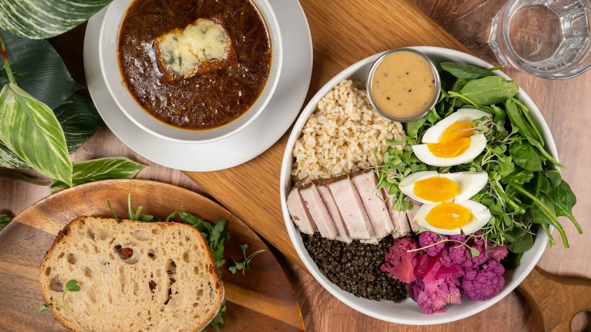 An overhead spread of French onion soup, a grain bowl, and house-baked bread at The Porch Kitchen