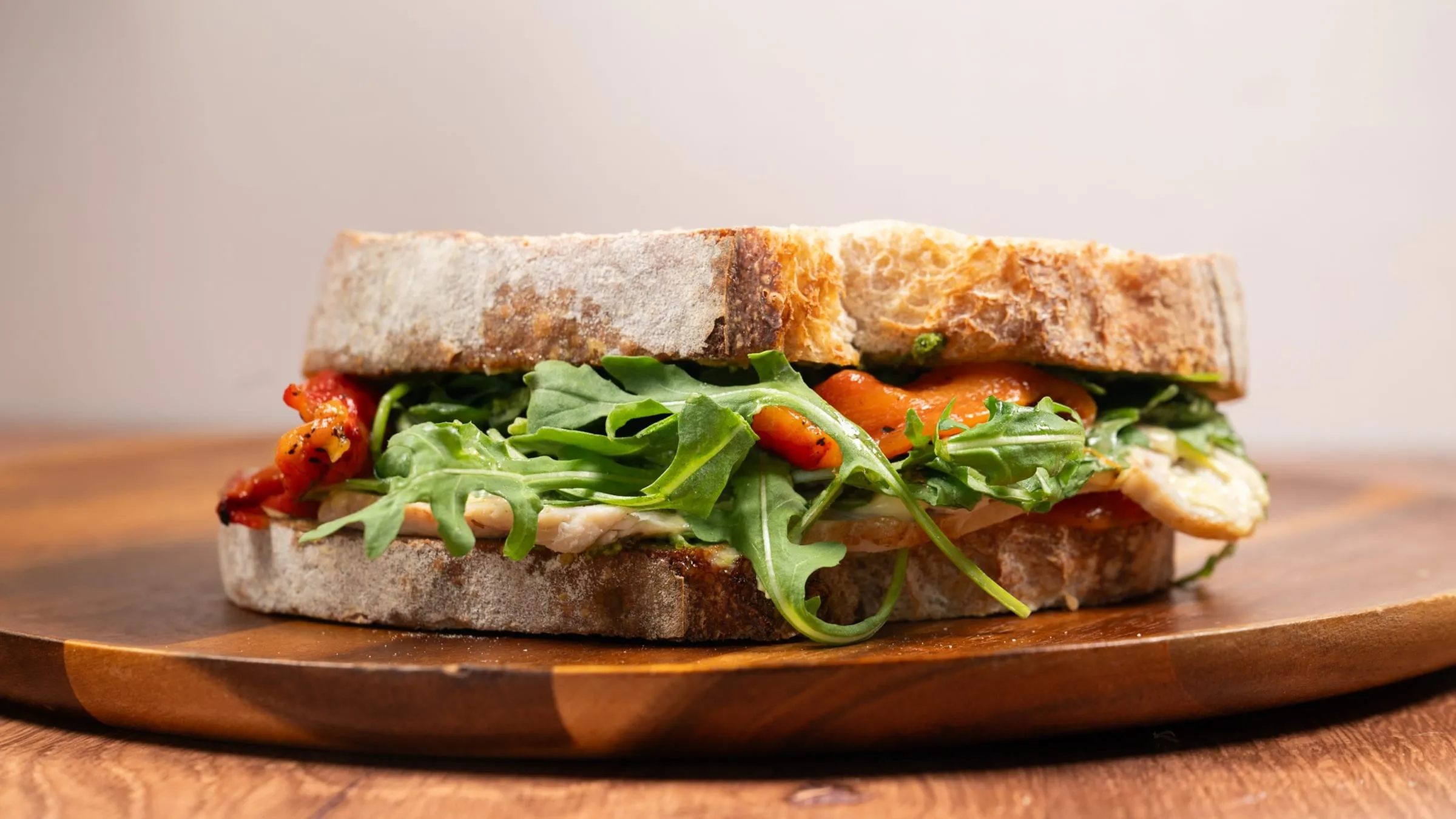 A house-made turkey sandwich with arugula and roasted peppers on artisan bread